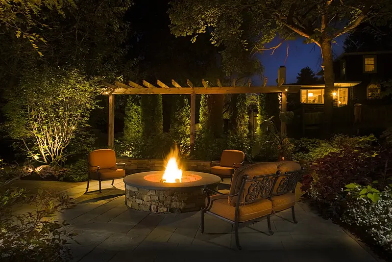 Outdoor fire pit with visible flame and surrounding patio seating