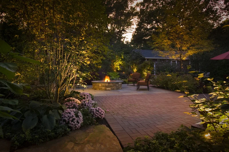 Brick patio with stone fire pit and landscape lighting