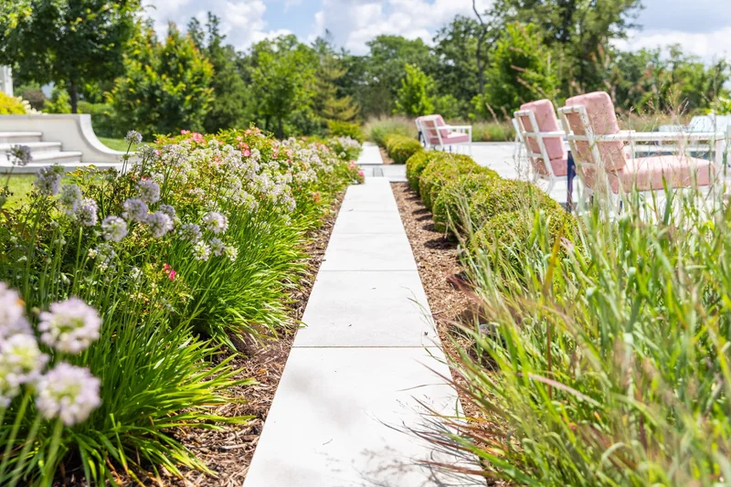 Paver walkway and patio border through flowering landscape beds