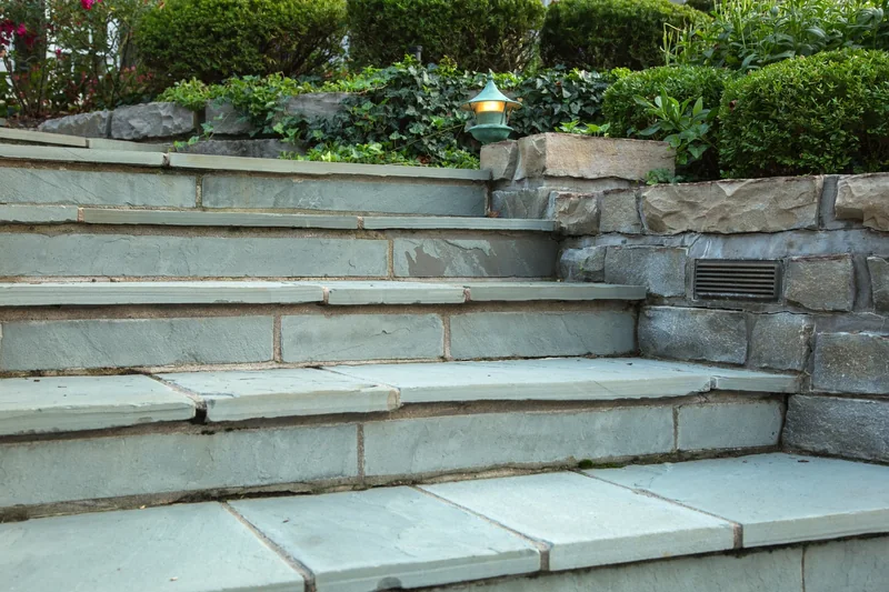 Stacked stone wall bordering a walk and planting bed